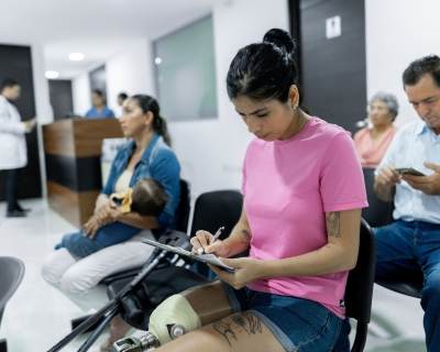 doctor's office waiting room A woman with a prosthetic leg fills out forms in the waiting room of a medical office. A mother and baby, an older woman, and a middle-aged man also sit waiting.